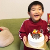 7歳の誕生日ケーキをもつ息子