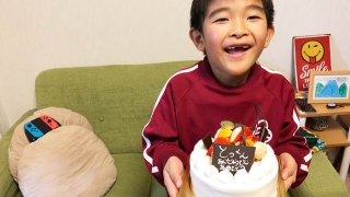 7歳の誕生日ケーキをもつ息子