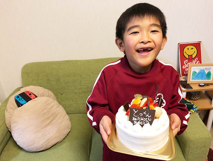 7歳の誕生日ケーキをもつ息子