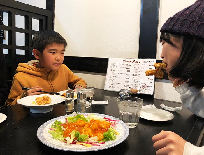 唐揚げを食べる姉を見る弟