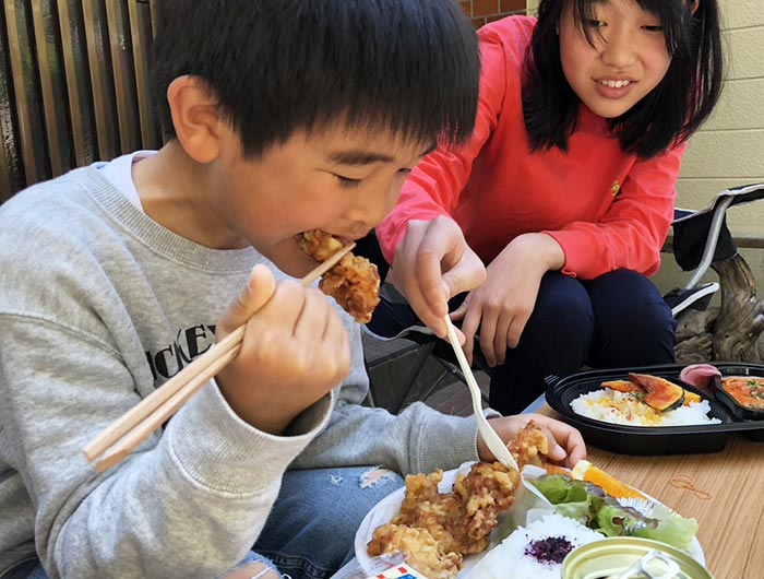 唐揚げ弁当を食べる姉弟