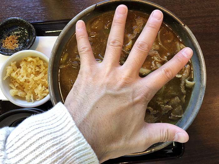 肉カレーうどんに手をあてる